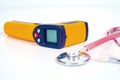 Yellow Infrared thermometer gun used to measure temperature with stethtoscope on white background