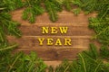 Yellow inscription New Year on a wooden background. Frame of fir