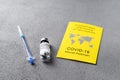 Yellow International Certificate of Vaccination, syringe, vial with vaccine on gray table