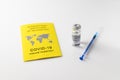 Yellow International Certificate of Vaccination, syringe, vial with vaccine on white table