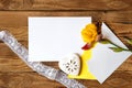 Yellow iris flower, white sheet of paper, heart and lace ribbon on a wooden background. Flat layout with space for text Royalty Free Stock Photo