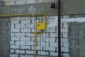 Yellow iron pipe and gas meter on a dirty white brick wall Royalty Free Stock Photo