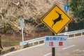 A yellow Japanese language road traffic sign of beware jumping wild deer into the road at nara national park.