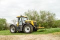 Yellow JCB Fastrac tractor parked by hedge