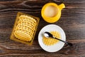 Yellow jug with condensed milk, box with cookies, cookie and spoon in saucer on wooden table. Top view Royalty Free Stock Photo