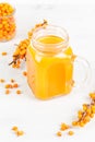 Yellow juice in a glass mug. Close-up on a white background, with sea buckthorn twigs.