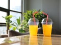 Yellow juice glasses or plastic disposable glasses with straws on table blurry background