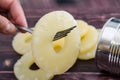 Yellow juicy pineapple ring on a fork against the background of a tin can. Caramelized canned pineapple. Raw food diet. Close-up p Royalty Free Stock Photo