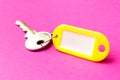 Yellow key tag on a purple textured cardboard background.The concept of rent, selling. Template. Trend colors