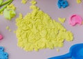 Yellow kinetic sand and molds on a pink table