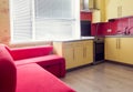 Yellow kitchen with cupboards, window, laminate and red soft couch
