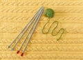 Yellow Knitted Background with Pattern and Braids;Grey Knitting Needle and Green Ball.Hand Made