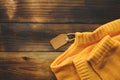 Yellow knitted sweater with price tag on old wooden background top view. Fashion Lady Clothes Set Trendy Cozy Knit