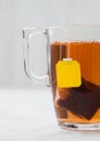 Yellow label tag black tea teabag in clear glass cup on white