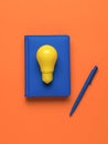 A yellow lamp, a notebook with a pen on an orange background. Flat lay Royalty Free Stock Photo