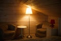 A yellow lampshade shines dimly and comfortably in the attic bedroom with a low ceiling. Lamp near the bed.