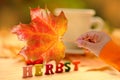 yellow leaf in female hand, tea, coffee in mug on the table in garden, colored letter words, concept of happy Thanksgiving, Royalty Free Stock Photo