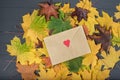 Yellow leaves and craft envelope on a gray wood background. Envelope with heart Royalty Free Stock Photo