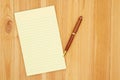 Yellow legal lined notepad paper with a pen on pine wood desk Royalty Free Stock Photo