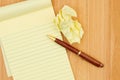 Yellow legal notepad paper with crumpled paper and pen wood desk Royalty Free Stock Photo