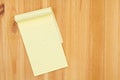 Yellow legal notepad paper with lines on pine wood desk Royalty Free Stock Photo