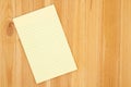 Yellow legal notepad paper with lines on pine wood desk Royalty Free Stock Photo