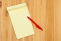 Yellow legal notepad paper with pen on pine wood desk Royalty Free Stock Photo