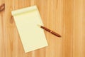 Yellow legal notepad paper with pen on pine wood desk Royalty Free Stock Photo