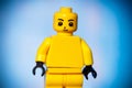 yellow lego figurine with joy on his face on a blue background with a vignette