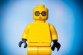 yellow lego figurine with joy on his face on a blue background with a vignette