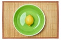 Yellow lemon on a green plate on a cane place mat