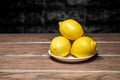 Yellow lemon in a plate on a wooden close-up table and dark background