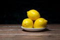 Yellow lemon in a plate on a wooden table and dark background