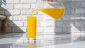 Yellow lemonade against white brick wall background, pour orange juice into glass. Orange juice in a glass Royalty Free Stock Photo