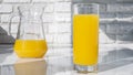 Yellow lemonade in a glass against the background of a white brick wall. Orange juice in a jug and in a glass on the kitchen table Royalty Free Stock Photo