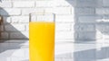 Yellow lemonade in a glass against a white brick wall background. Orange juice in a glass Royalty Free Stock Photo