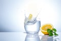 Yellow lemons in a glass and splashes of water. Tasty and healthy food. Seasonal drinks