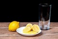 Yellow lemons with lemon pieces on a ceramic plate and a glass behind Royalty Free Stock Photo