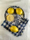 yellow lemons on a plate with a blue pattern and a checkered napkin on a white background Royalty Free Stock Photo