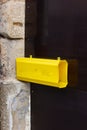 yellow letterbox on dark wooden door