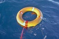 Yellow lifebuoy with a rope in blue sea on water. Life ring floating on top of water. Life ring with a rope in ocean Royalty Free Stock Photo