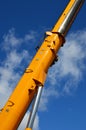 Yellow lifting crane-arm against the blue sky with white clouds at building site on sunny day Royalty Free Stock Photo