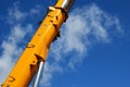 Yellow lifting crane-arm against the blue sky with white clouds at building site on sunny day Royalty Free Stock Photo