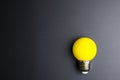 Yellow light bulb on black background with copy space. Royalty Free Stock Photo
