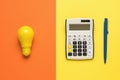 A yellow light bulb, a calculator and a blue pen on an orange and yellow background Royalty Free Stock Photo