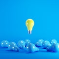 Yellow light bulb floating among blue light bulbs on background.