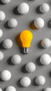Yellow light bulb standing out from white spheres on gray background, creativity and individuality concept Royalty Free Stock Photo