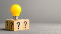 Yellow light bulb on wooden blocks with question marks symbolizing creative idea and problem solving concept Royalty Free Stock Photo