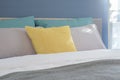 Yellow, light gray and green pillows setting on bed in modern interior bedroom Royalty Free Stock Photo
