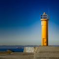 Yellow lighthouse on breakwater dam Royalty Free Stock Photo